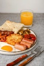 English breakfast with fried eggs, hash brown, sausages, bacon, beans, toasts, mushrooms, tomato and...