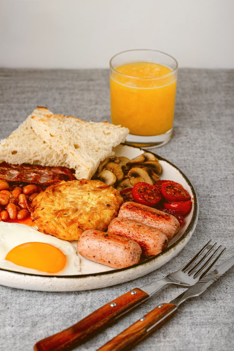 English breakfast with fried eggs, hash brown, sausages, bacon, beans, toasts, mushrooms, tomato and...