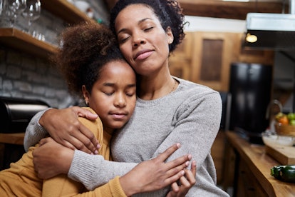 Single black mother embracing her little daughter at home.