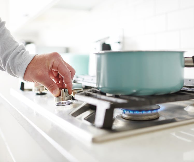 Unidentifiable male cooking food on a gas stove