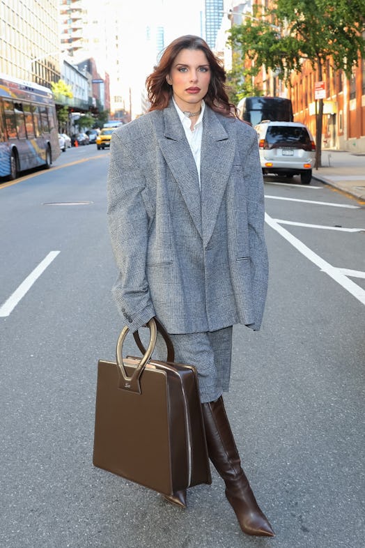 Julia Fox wears a gray suit and large luar bag.