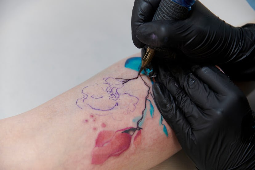 Female young tattooist creating flower tattoo art, in a story about tattoos artists are tired of dra...