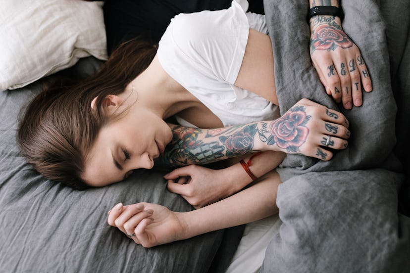 Overhead view of couple sleeping in Bed together, in a story about tattoo designs tattoo artists are...