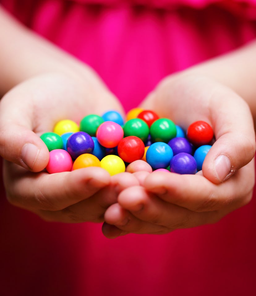 Young girl holding rainbow colored gum balls.