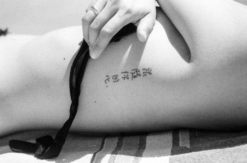 Tattoo in Chinese characters on a woman's ribs saying "follow your heart," in a story about tattoos ...