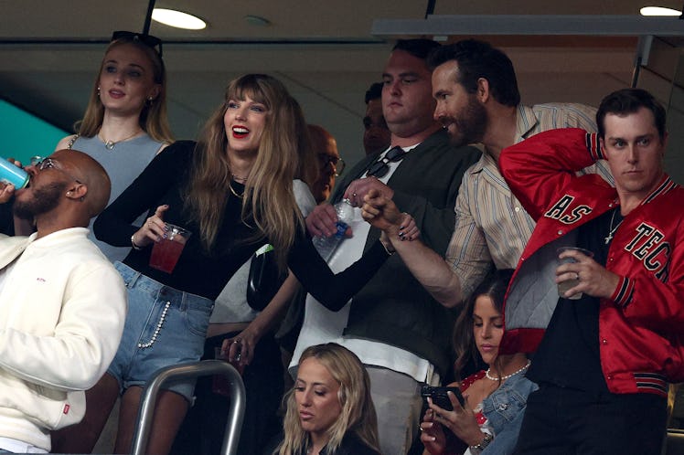 Taylor Swift with a Betty Buzz red drink in hand, chats with Ryan Reynolds the Kansas City Chiefs ga...