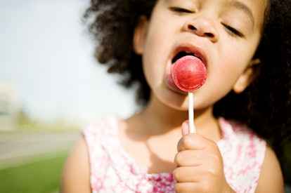 Child with Afro licking red lollipop. Does red food dye change kids behavior?