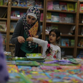 A mother and daughter peruse books at a local book fair. 