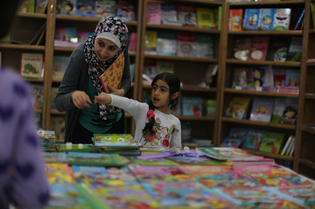 A mother and daughter peruse books at a local book fair.