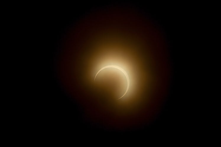 The moon crosses in front of the sun during the annular solar eclipse as smoke haze from fires in th...