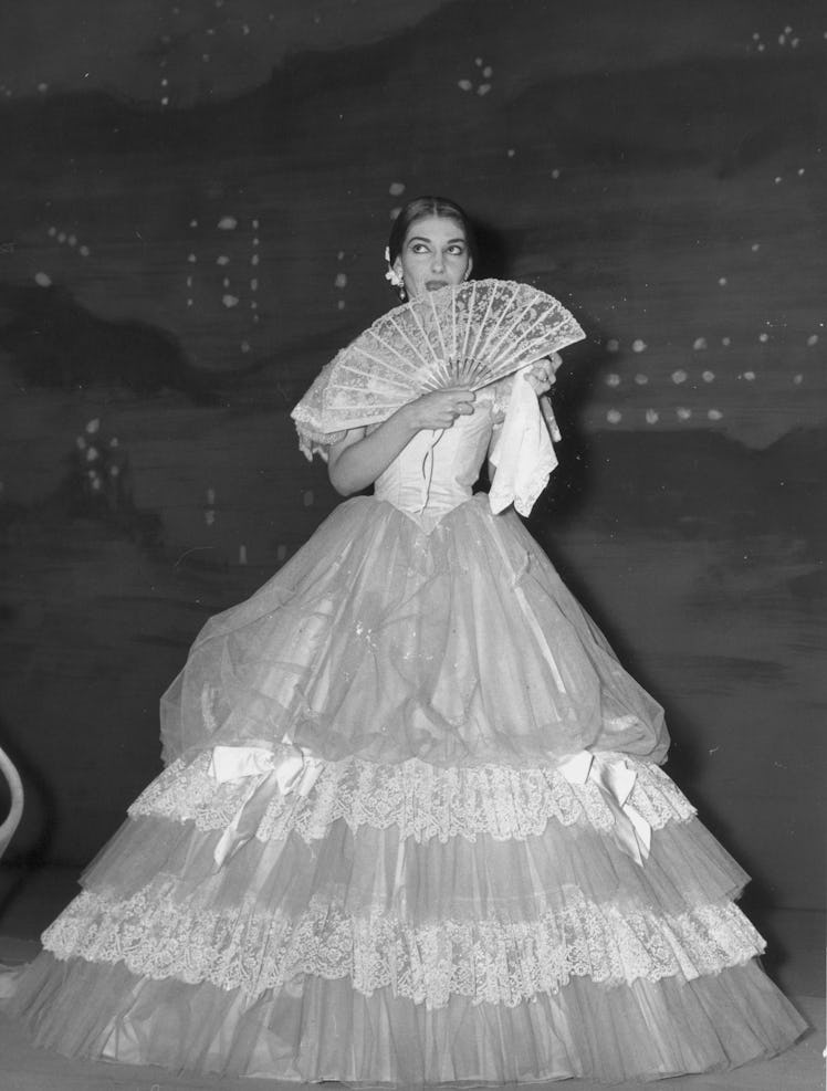 Greek-American opera singer Maria Callas (1923 - 1977), in costume, holds a fan while waiting in the...