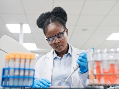 Young female scientist filling chemical through pipette while working in laboratory
