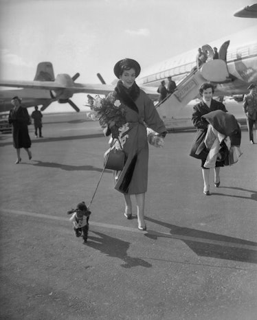 Maria Callas, with pet pooch in tow, leaves Idlewild after arrival here from Milan for a Carnegie Ha...