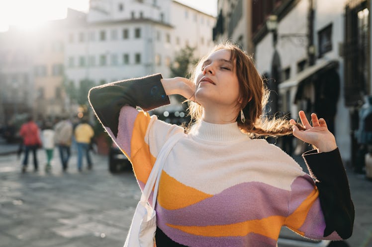 A woman is relaxing in the city at sunset. She's stretching and relaxing outdoor.