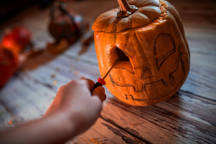 boy's Halloween tradition: creating pumpkin lanterns hands of a boy carving a pumpkin