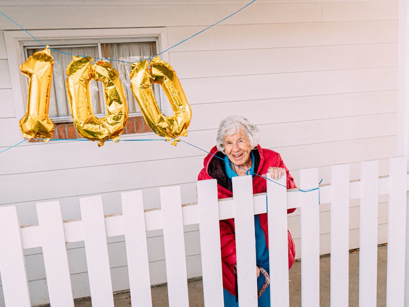 Wide Angle Shot of a Cheerful Elderly Senior Caucasian Woman Celebrating Her 100th Birthday with Gol...