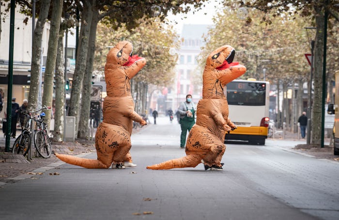 dpatop - 11 November 2020, Rhineland-Palatinate, Mainz: Two carnivalists in inflatable dinosaur cost...