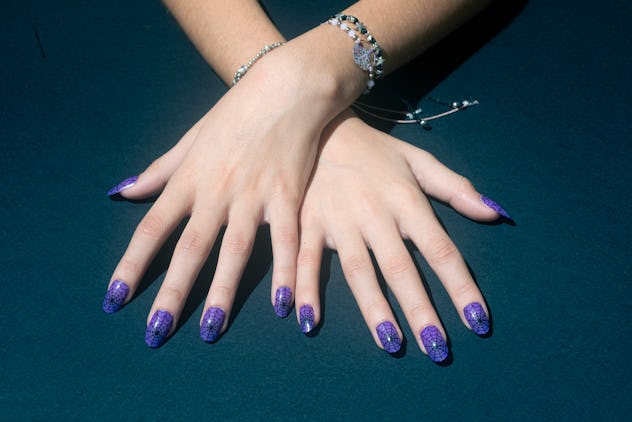 Female hands with false nails with drawn cobwebs on a blue background.Nail Art Manicure halloween na...