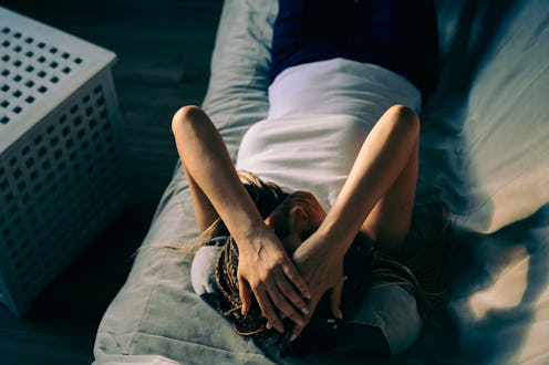Portrait of a dreadlocks braid topknot bun woman lying and sleeping on the sofa. Concept of depressi...
