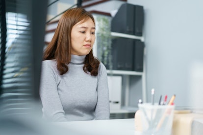 Portrait of unhappy - sad Asian female employee sitting in the office with her negative expressing. ...