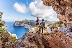 Capo Caccia, hikers admiring the view from a cave. Sardinia island, Italy