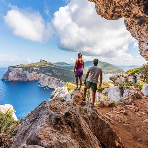 Capo Caccia, hikers admiring the view from a cave. Sardinia island, Italy