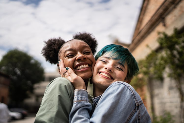 two friends share a hug in the street as they consider the luckiest signs of November 2023
