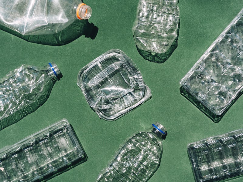 Transparent plastic garbage on green background, top view. The concept of recycling and zero waste.