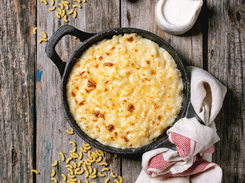 Classic american dish baked mac and cheese in cast iron pan with kitchen towel and ingredients above...