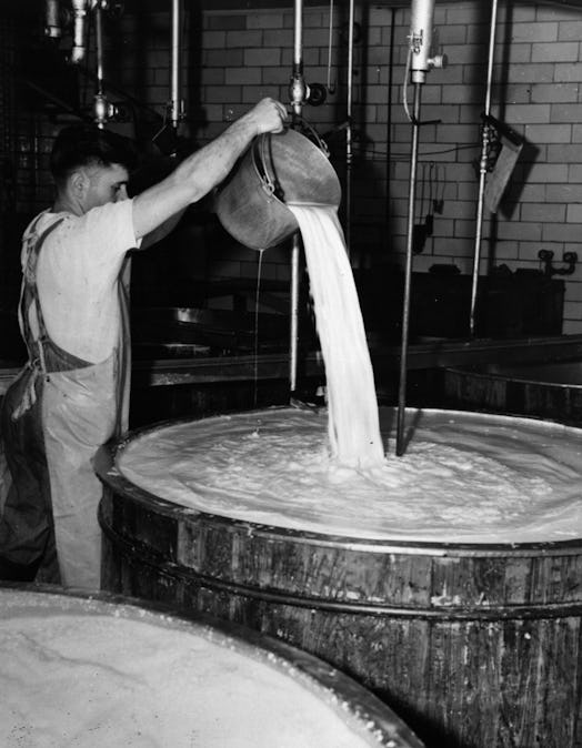 circa 1940:  A farmer adding an extra bucket of milk to enrich his cheese.  (Photo by Three Lions/Ge...