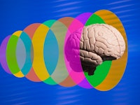 Human brain going through translucent multi colored discs blue background