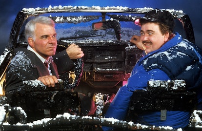 Steve Martin and John Candy sit in a destroyed car in a scene from the film 'Planes, Trains & Automo...