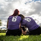 Rear view of female soccer players sitting on ground outdoors