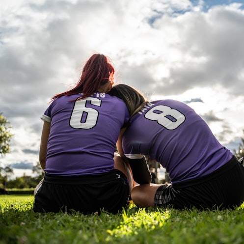 Rear view of female soccer players sitting on ground outdoors