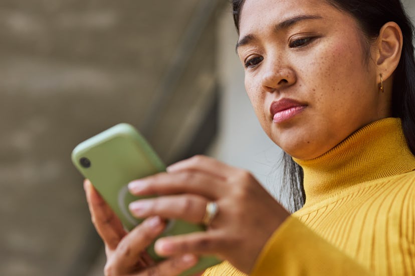 Close-up of woman reading text message on cellphone outdoors