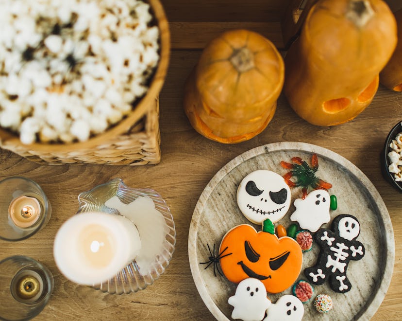 Wooden table. Traditional food and snacks for Halloween party. Fresh cookies in ghosts, monsters, sk...