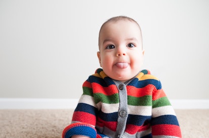 Infant baby poses for camera after learning to sit up, in an article about tongue tie in babies