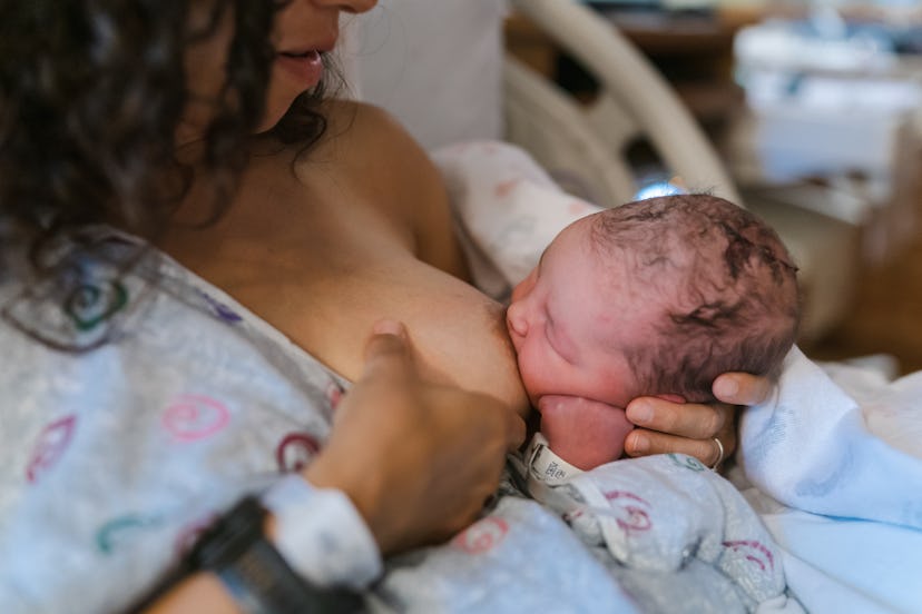 Woman breastfeeding her newborn baby while sitting in a hospital bed, in an article about tongue tie...