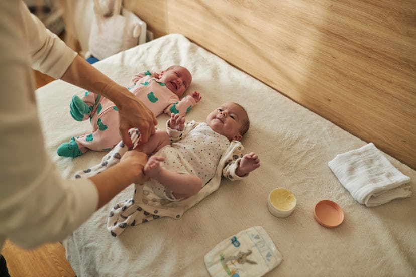 Mother dressing newborn twin babies in a story about new mom affirmations.