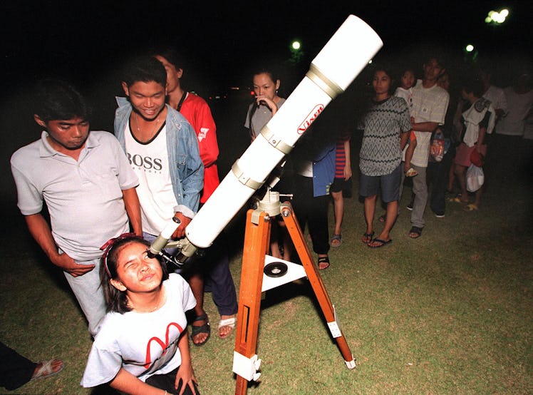 AYUTTAYA, THAILAND:  A young stargazer looks through a telescope as others queue for a view of the L...