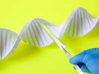 Modifying DNA (deoxyribonucleic acid), conceptual image. A gloved hand uses tweezers to carefully re...