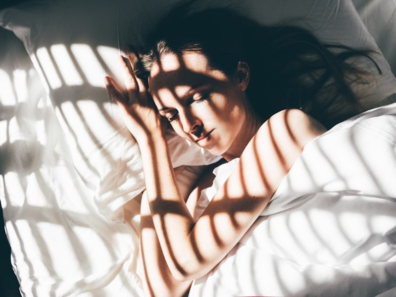 Beautiful young woman sleeps in a comfortable bed. Sunbeam of dawn on her face.