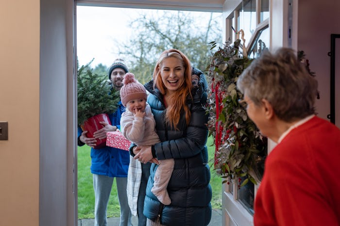 An over the shoulder, medium shot of a senior woman opening her front door to her three grandchildre...