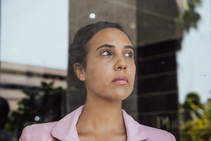 Young businesswoman contemplating looking through the window at office