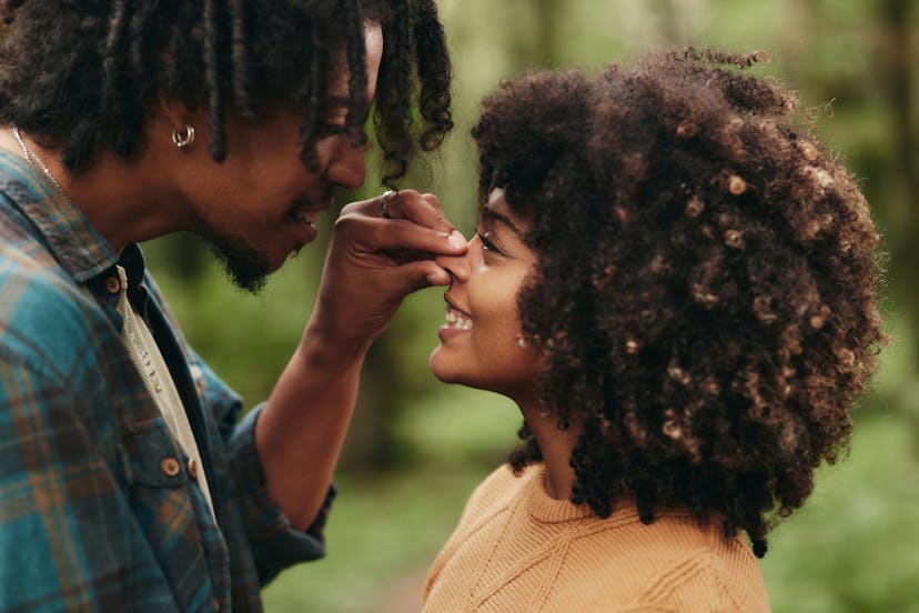 Loving black man pinching his girlfriend's nose during autumn day in the woods.