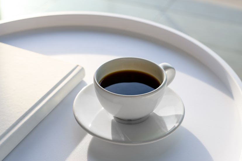 White coffee cup and a white book on a white coffee table