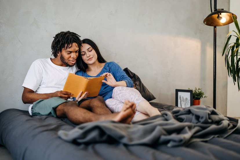 Young woman and man relaxing in bed with a book