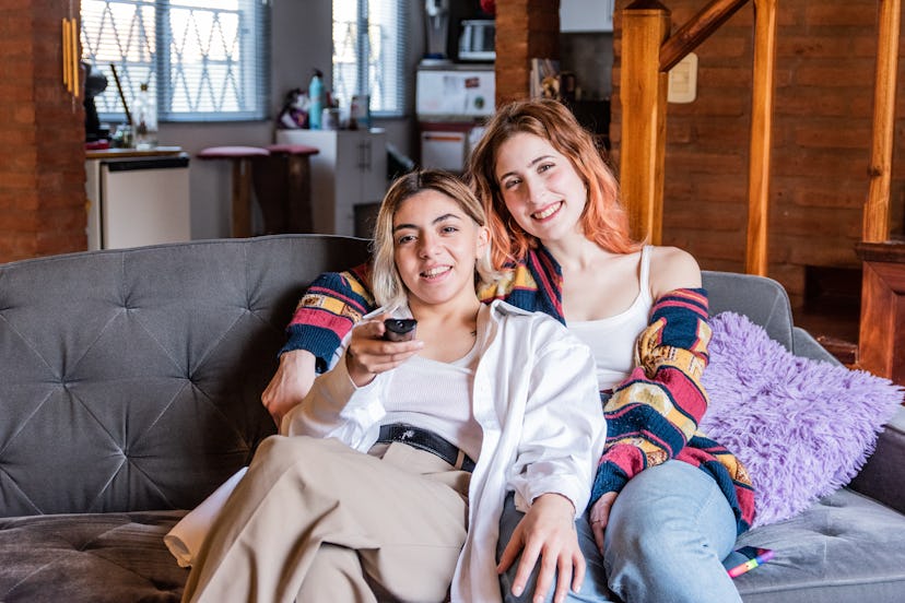 Portrait of a young lesbian couple watching tv/movie sitting on sofa at living room