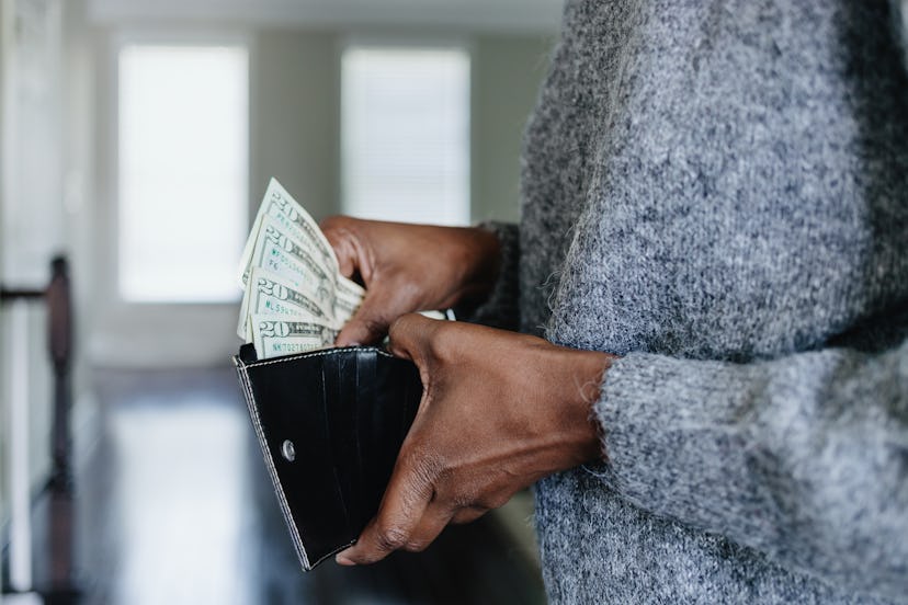 Close-up of unrecognizable black woman inserting twenty dollar bills into her wallet
