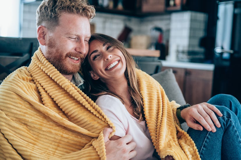 Shot of a cheerful young man hugging his girlfriend on the sofa at home.